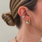 Close-up of a woman's ear wearing multiple 14k yellow gold and white gold earrings, including a pavé ear cuff. 