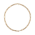 A gold paperclip chain necklace laid out on a plain background.