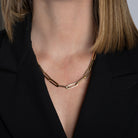 A person wearing a 14k gold chunky paperclip chain and a black blazer. 