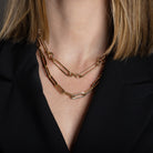 A person wearing two chunky 14k gold necklaces and a black blazer. 