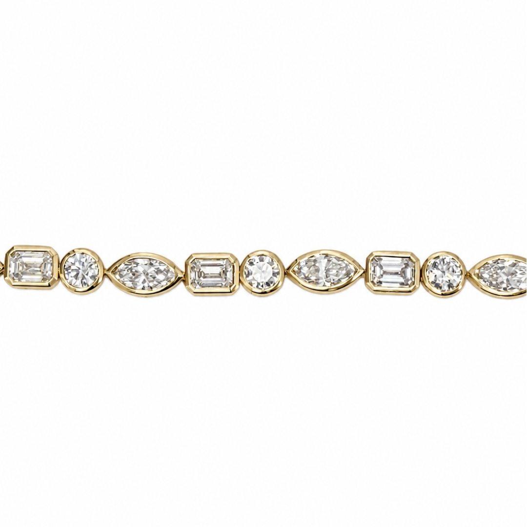 A close-up of a yellow gold tennis bracelet featuring a continuous row of round, emerald-cut, and marquise-cut diamonds on a plain white background.
