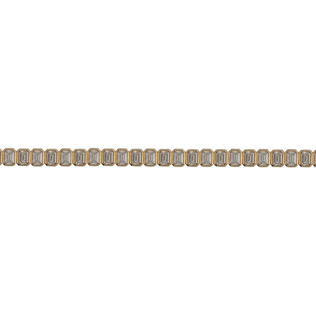 A close up of a lab-grown diamond tennis bracelet with emerald shaped diamonds in a north-south orientation. Bezel set in 14k gold against a white background. 