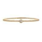 Gold bracelet with a single station diamond on a white background