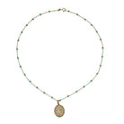 Necklace with turquoise beads and a pave diamond gold pendant on a white background